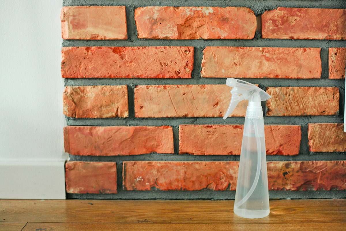 Spray bottle against a brick wall inside a home