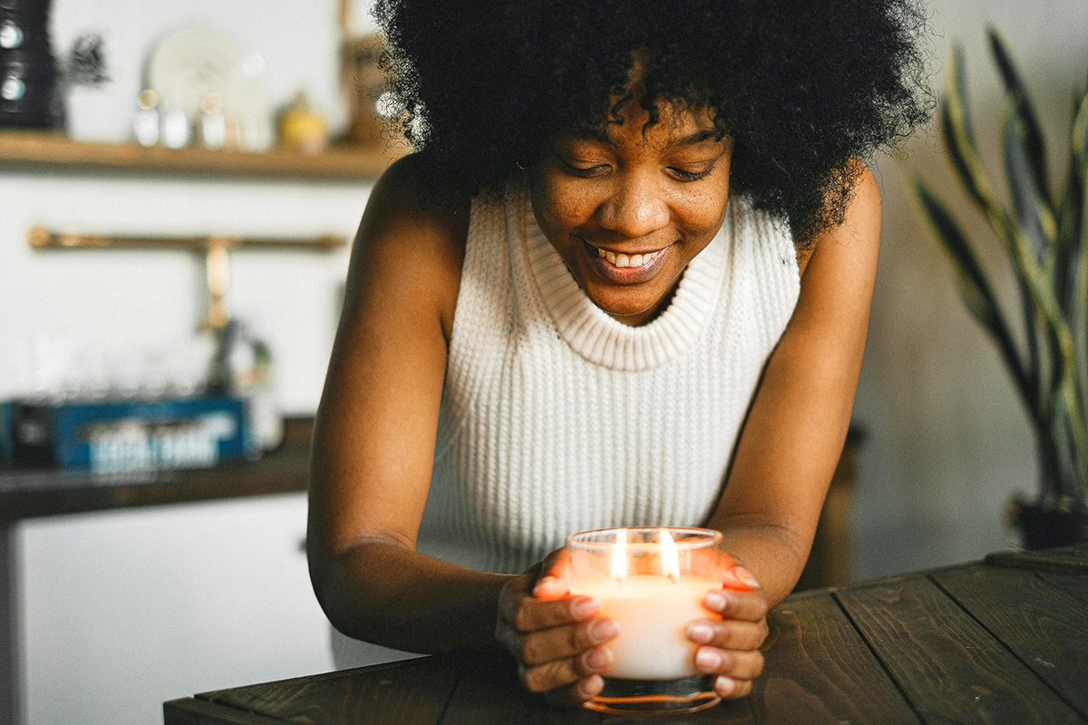 Cheerful black woman with burning candle at home
