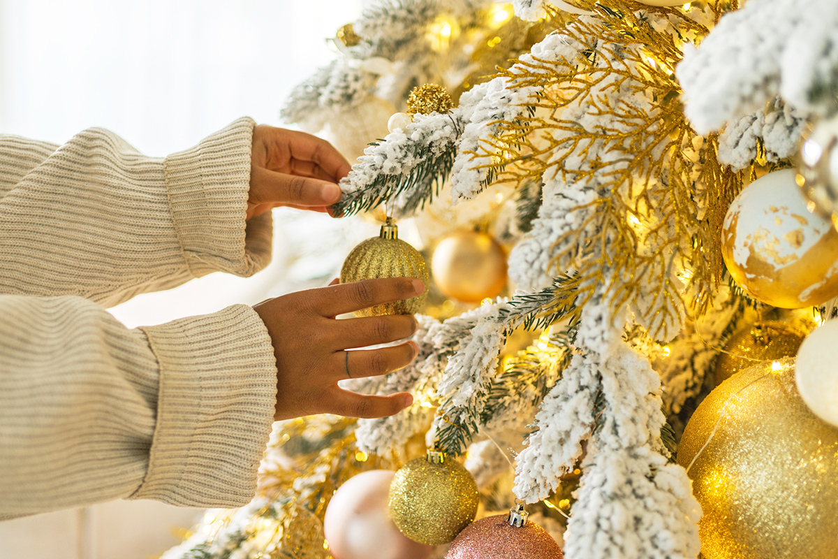 Close-up of a hand putting an ornament on a Christmas tree