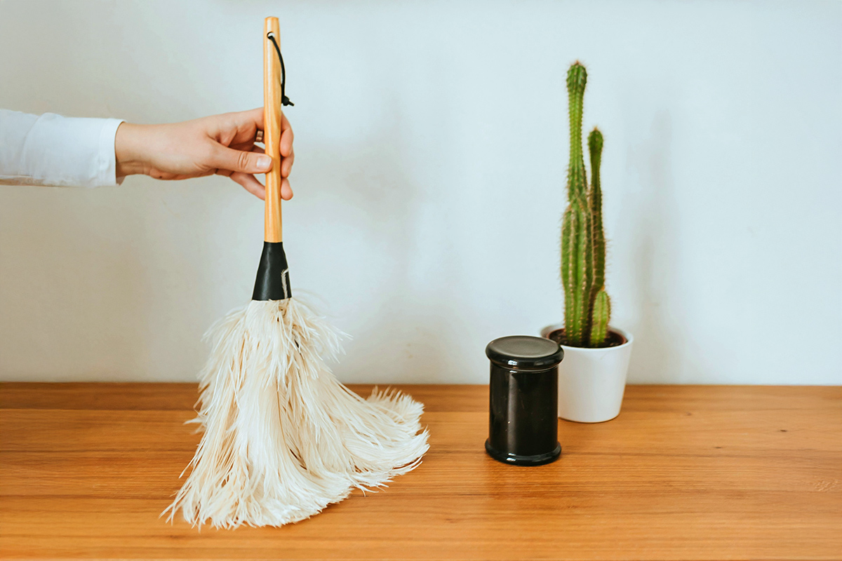 Close-up of cleaning entry way table with a duster
