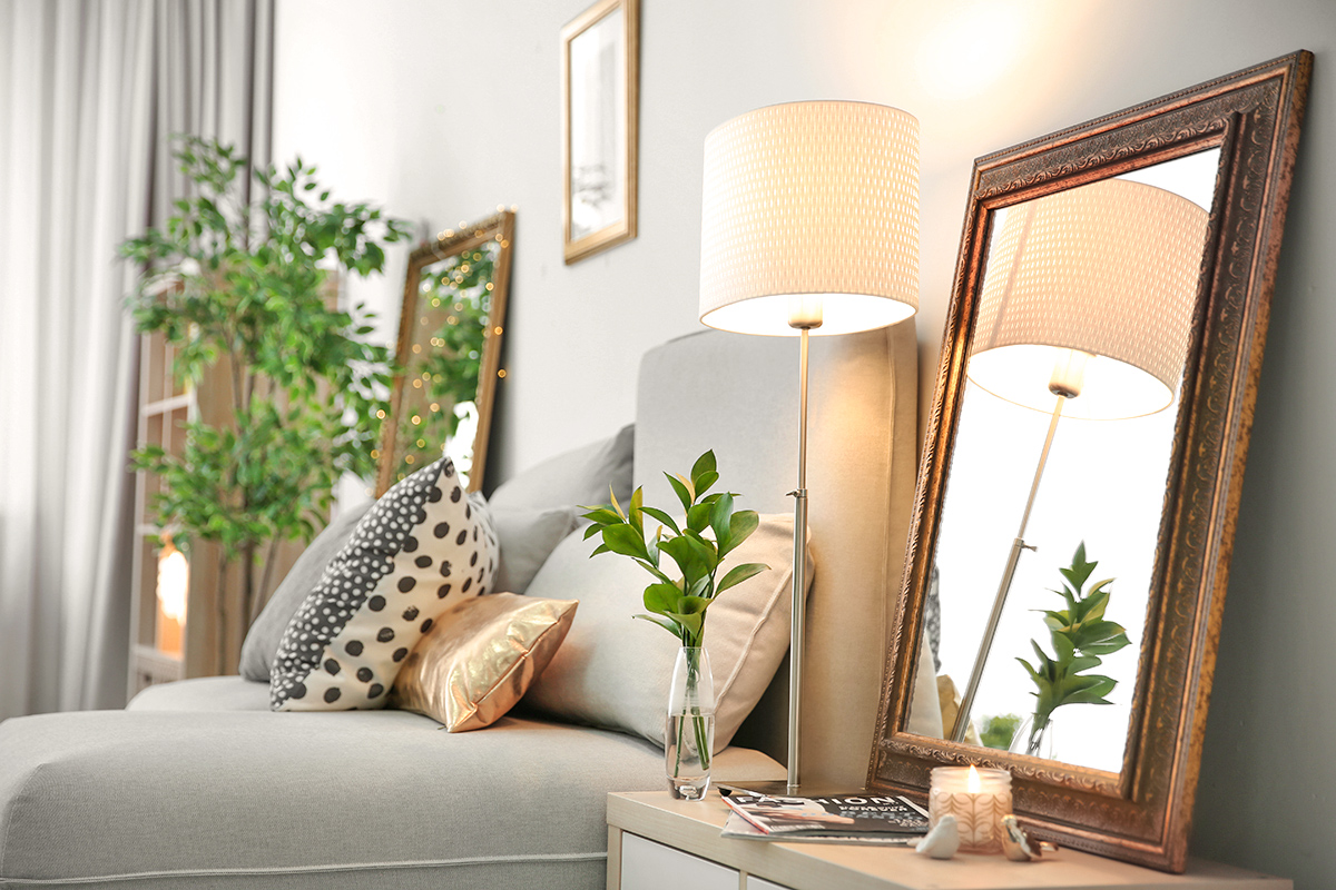 Elegant bedroom interior with mirror on nightstand 