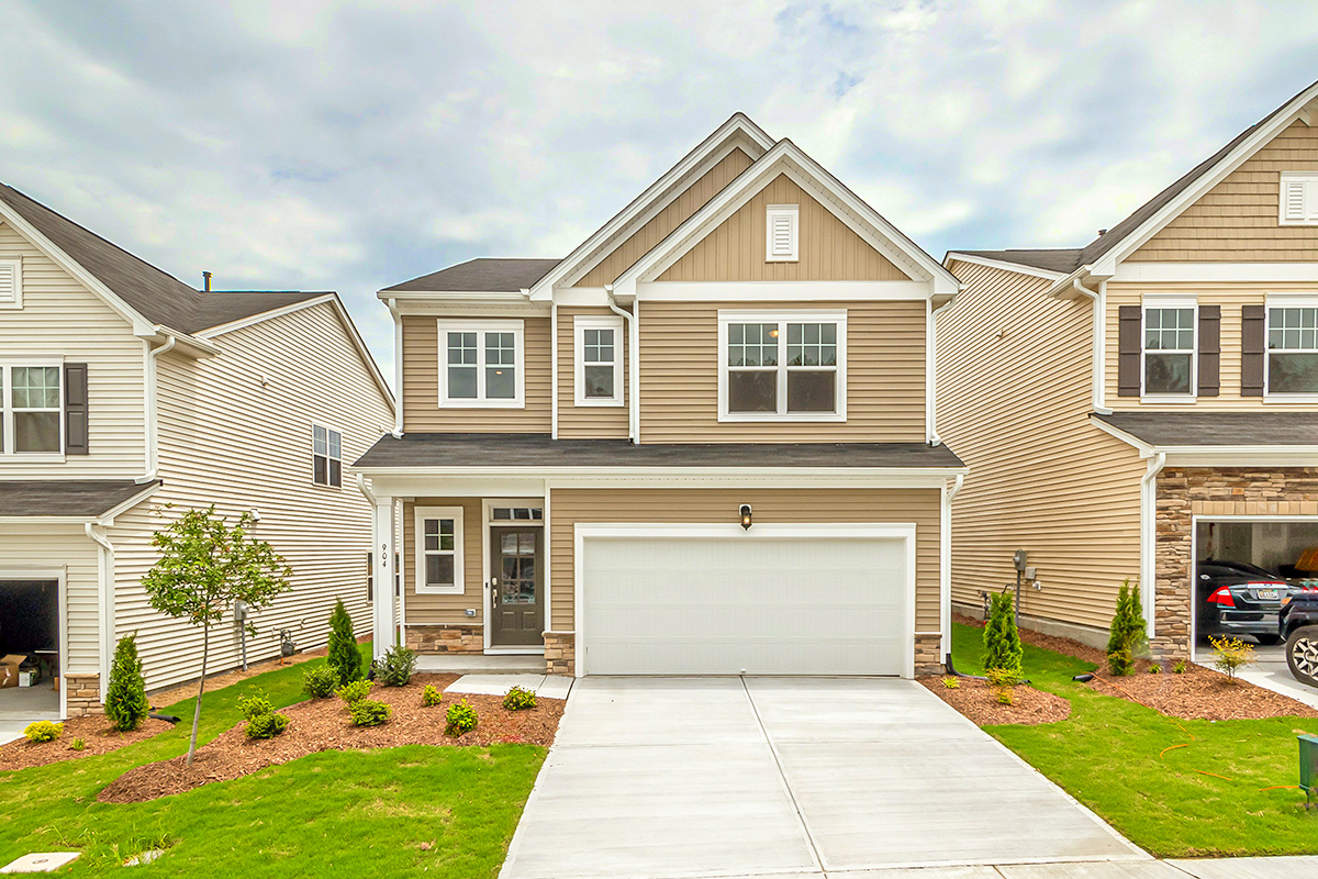 A two-story single-family home with a grassy front lawn and a concrete driveway.