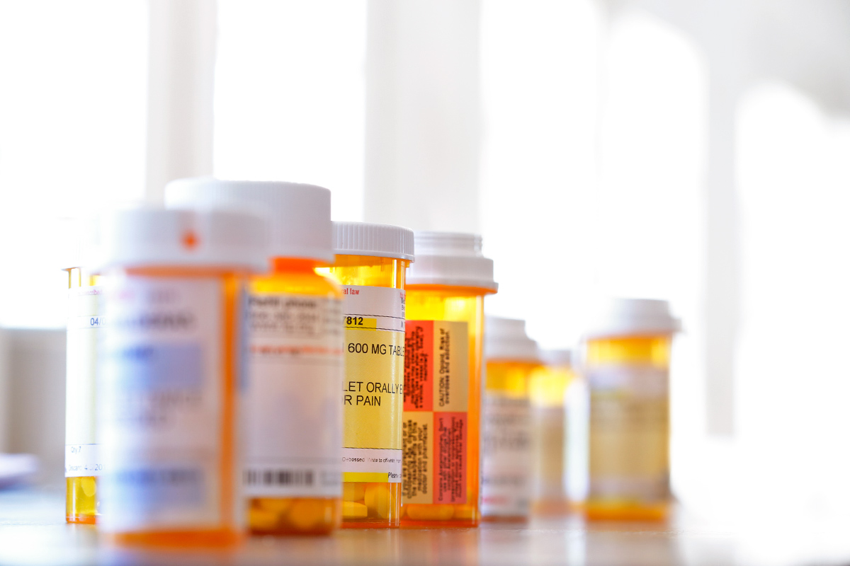 Bottles of medication (some in focus, some out of focus) lined up on a countertop.