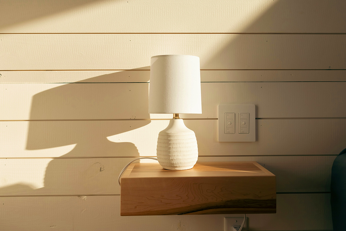 A white ceramic lamp with a visible cord on a floating bedside table.