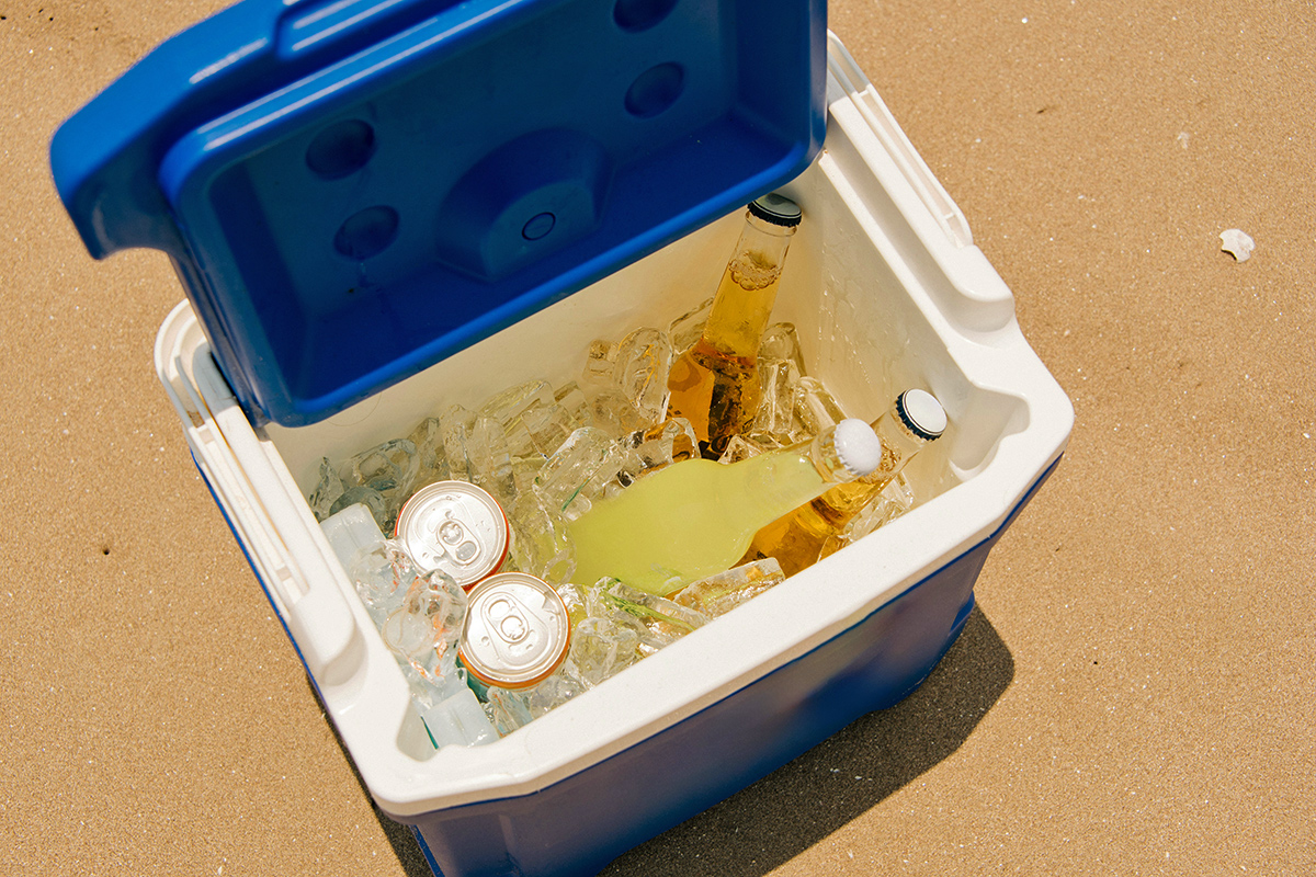 An open portable cooler with ice and drinks inside of it.