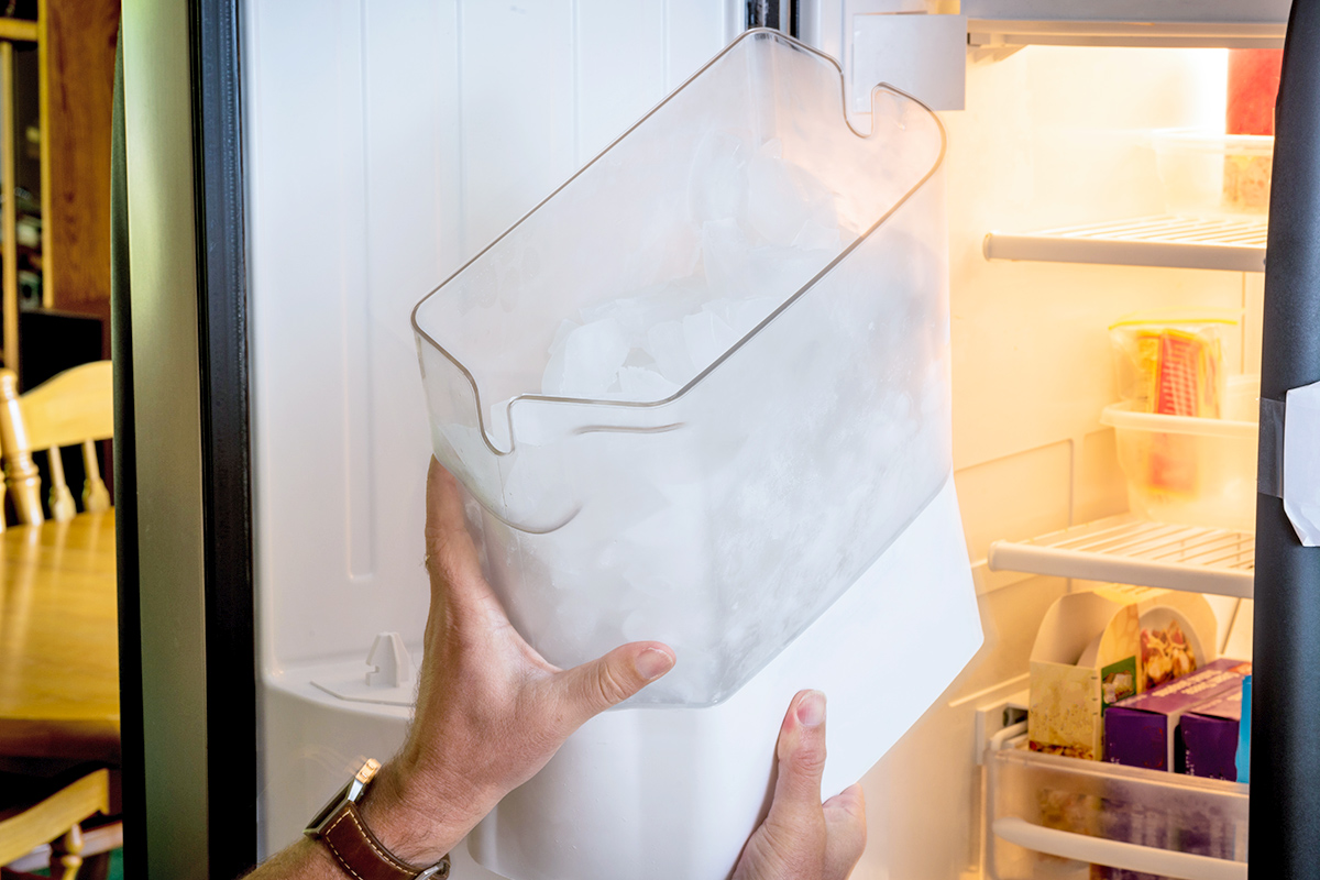 Anonymous person replacing the refrigerator door ice receptacle.